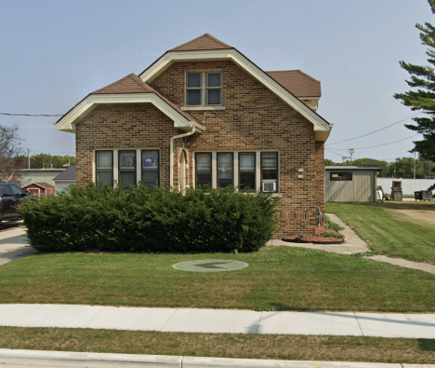 A brick house with a brown roof and a green lawn in front.