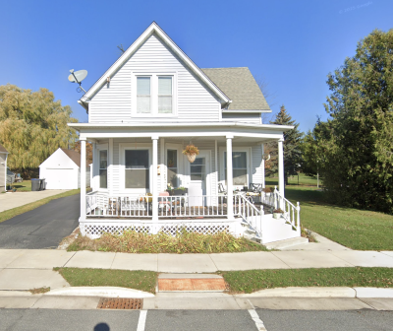 A white house with a grey roof and a porch.