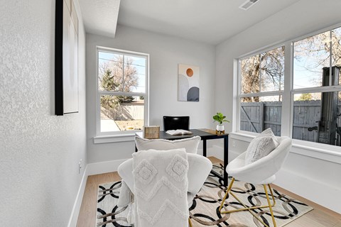 A white chair with a white blanket on it is in the middle of a room with a table and a plant.