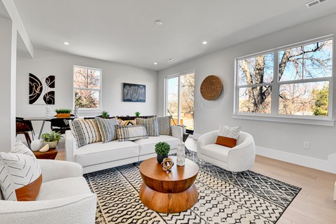A living room with a white couch, a coffee table, and a large window.