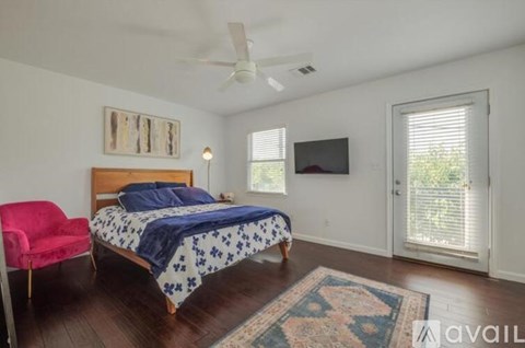 A bedroom with a bed, chair, and a rug.
