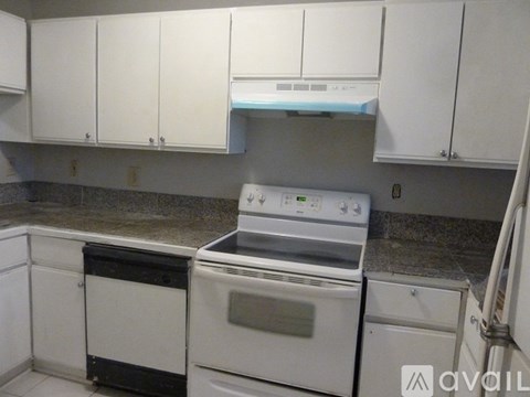 A white kitchen with a stove top oven and a dishwasher.
