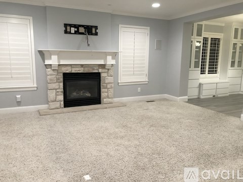 A living room with a fireplace and carpeted floor.