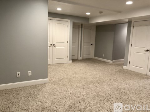 A room with grey walls and carpeted floor with four doors.