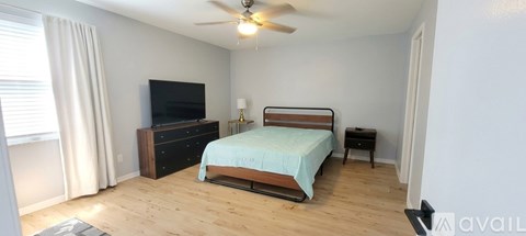 A bedroom with a bed, dresser, and television.