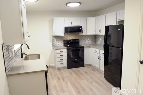 A kitchen with black appliances and white cabinets.