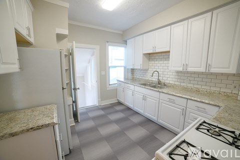 A kitchen with white cabinets and a marble countertop.