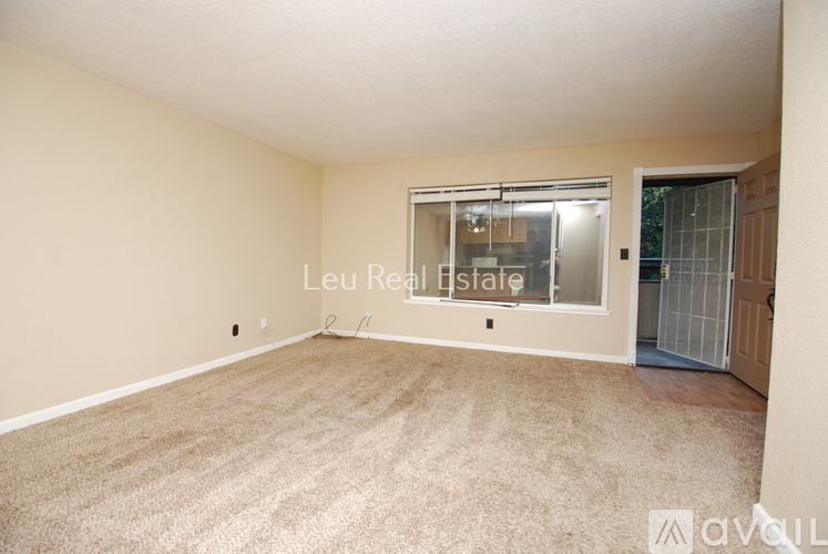 A room with a carpeted floor and a window with blinds.
