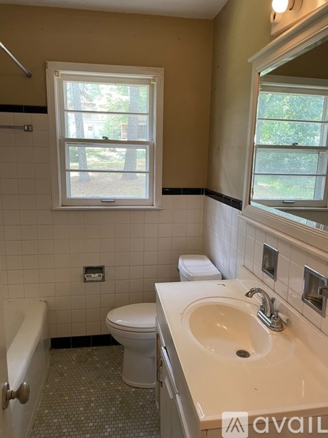 A bathroom with a toilet, sink, and window.