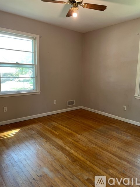 A room with wooden flooring and a ceiling fan.