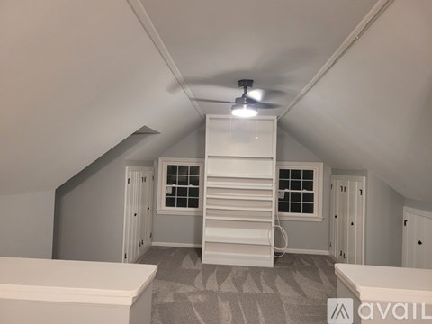 A room with a white ceiling fan and a staircase leading to another room.
