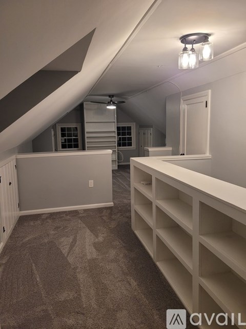 A room with a carpeted floor and a staircase leading to another room.