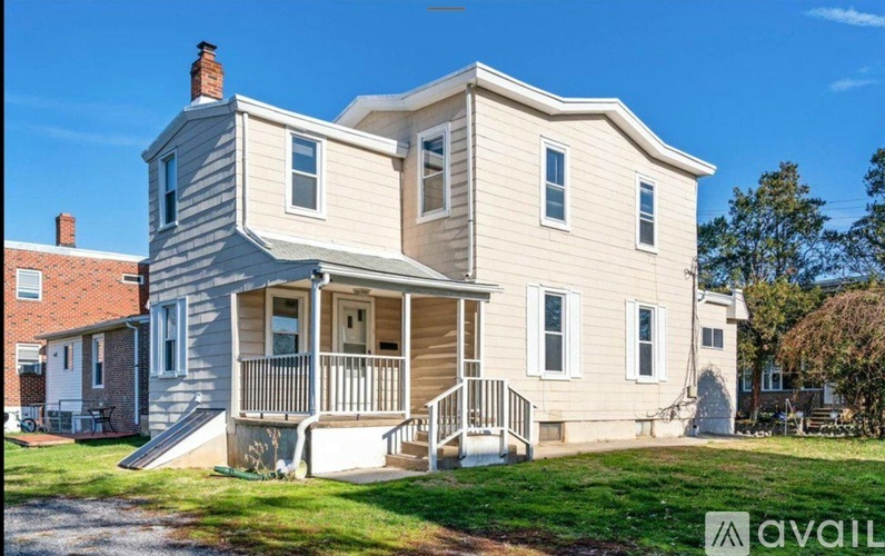 A two-story house with a front porch is for sale.