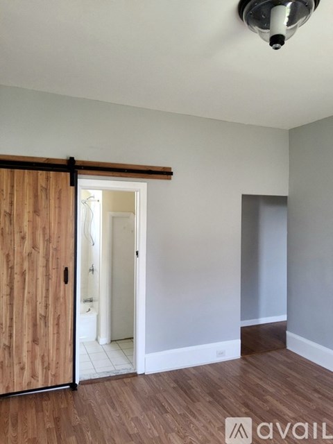 A room with a wooden door and a white wall.