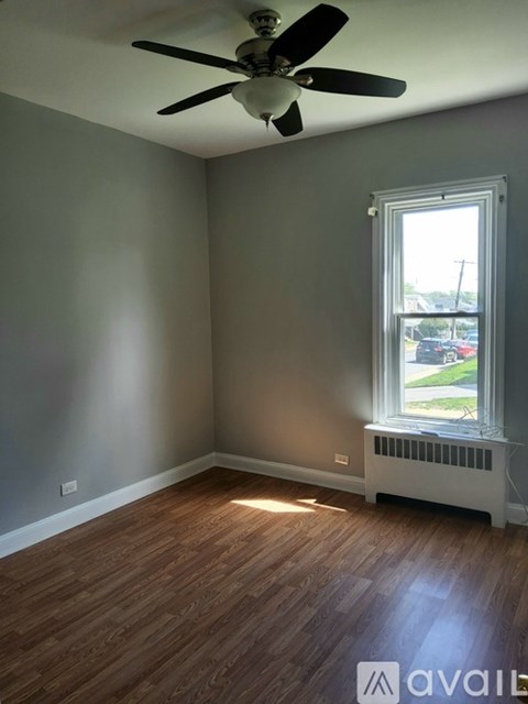 A room with a ceiling fan and a window with a view of the outside.