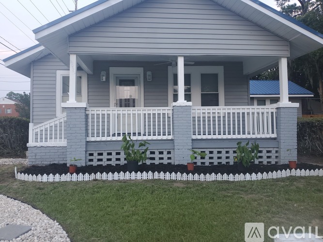 A small house with a porch and a white fence.