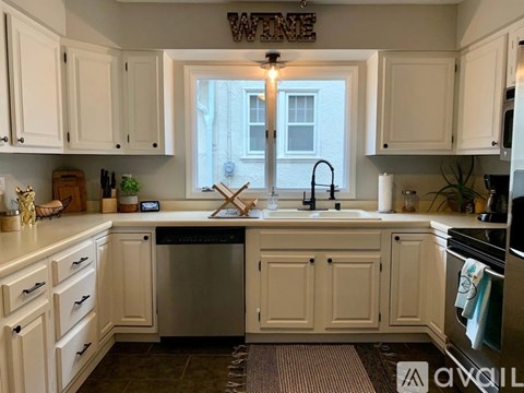 A kitchen with white cabinets and a window above the sink.