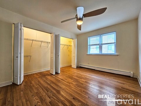 A room with a ceiling fan and a window with a view of a building outside.
