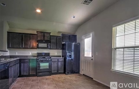 A kitchen with black cabinets and appliances.