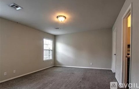 A room with a carpeted floor and a window with blinds.