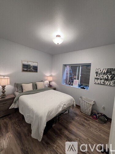 A bedroom with a bed, nightstand, and a poster on the wall.