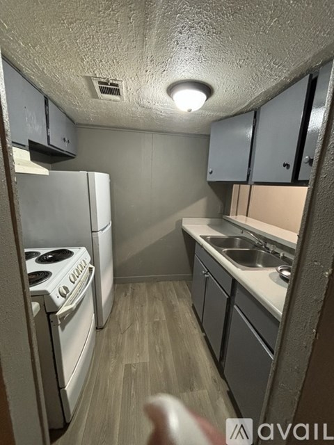 A kitchen with a stove, sink, and cabinets.