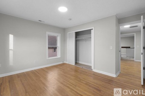 A spacious room with wooden floors and a large window.