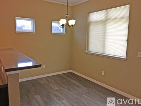 A room with a brown floor and a window with blinds.