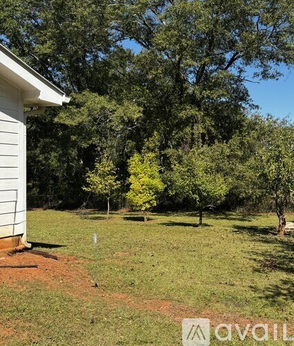 A yard with a white house and trees.