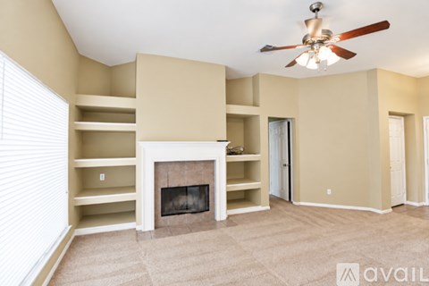 A living room with a fireplace and a ceiling fan.