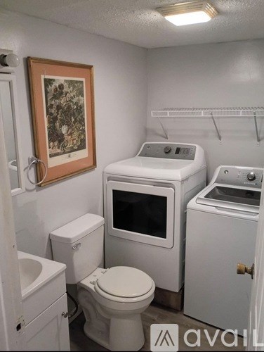 A small bathroom with a toilet, sink, and a washer and dryer.