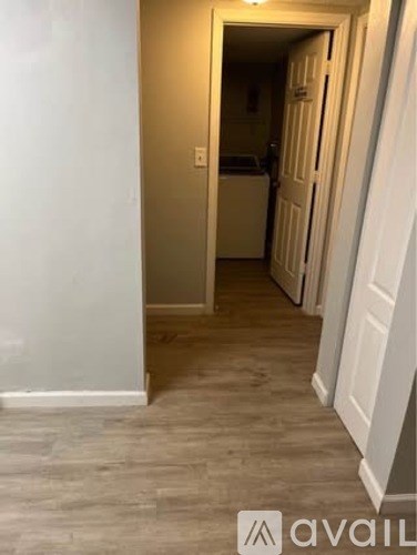 A hallway with a light on the wall and a door at the end.