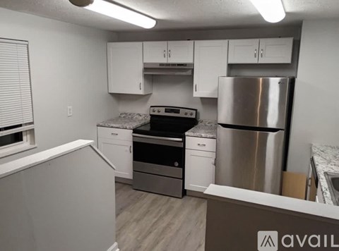 A kitchen with white cabinets and a stainless steel refrigerator.