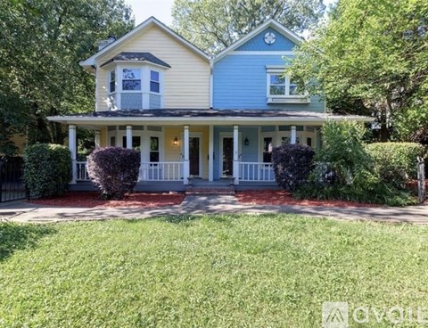 A blue house with a white porch and a red brick walkway.