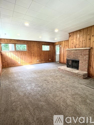 A living room with a fireplace and wooden walls.
