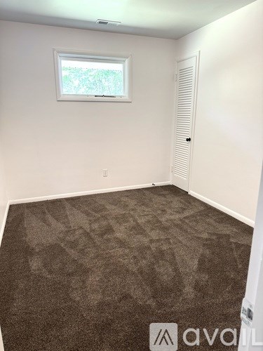 A room with a carpeted floor and a window.