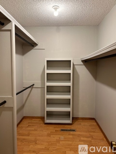 A white refrigerator with a black handle is in a room with wooden floors.