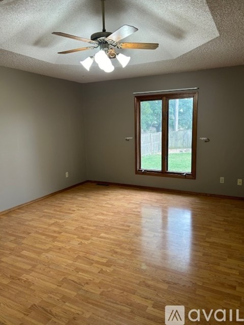 A room with a ceiling fan and wooden flooring.