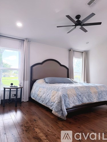 A bedroom with a large bed and a ceiling fan.