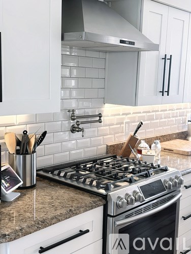 A modern kitchen with a stove top oven and white cabinets.