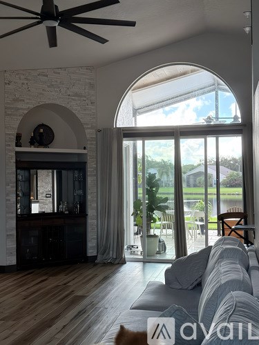 A living room with a grey couch and a ceiling fan.