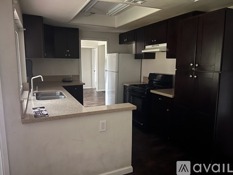 A kitchen with dark brown cabinets and a white counter.