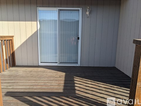A deck with a sliding glass door and a lamp on the wall.