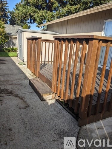 A wooden deck with a railing and a house in the background.