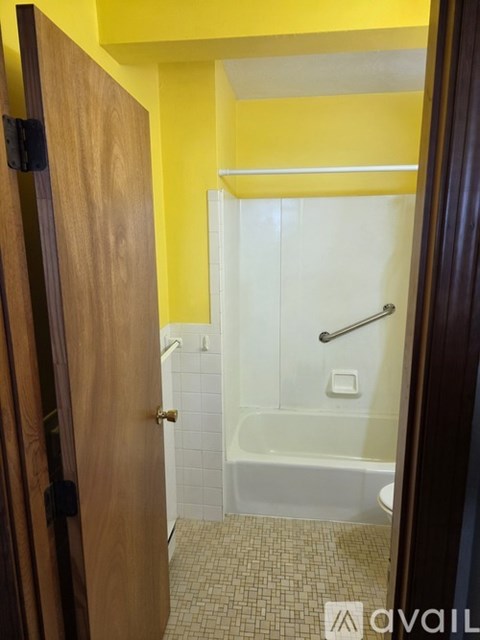 A bathroom with a yellow wall and a white bathtub.