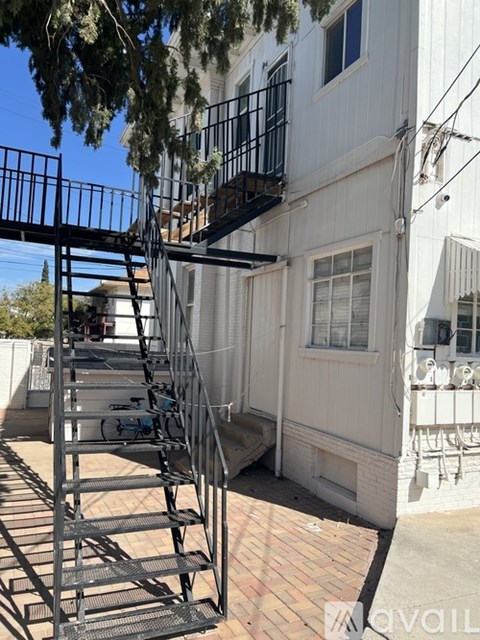 A metal staircase with a railing is in front of a white building.