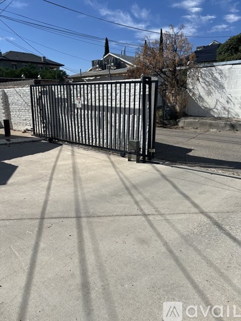 A black gate is closed on a concrete driveway.
