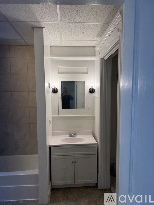 A bathroom with a sink, mirror, and cabinet.