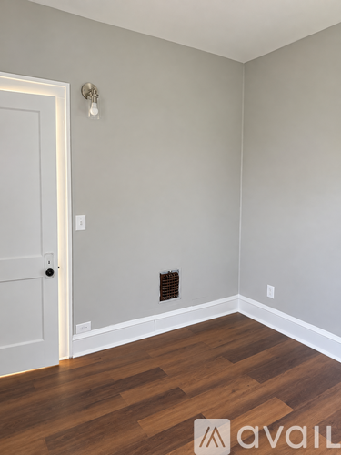 A room with a door and a light switch on the wall.