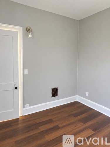 A room with a door and a light switch on the wall.